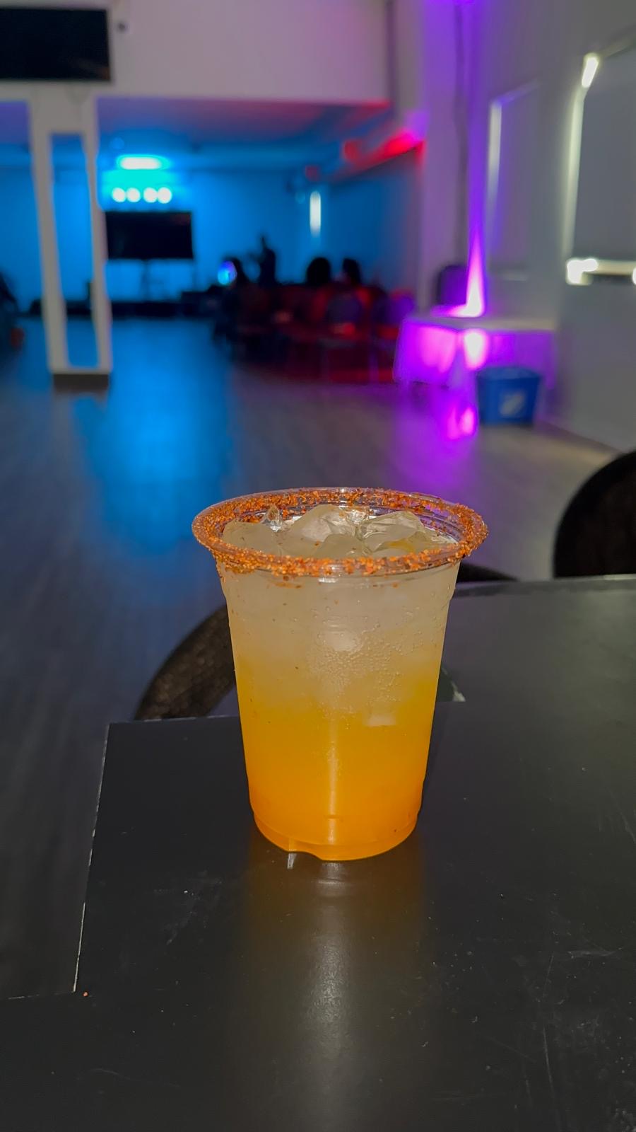 Chilli-rimmed orange mocktail on a table under purple event lighting
