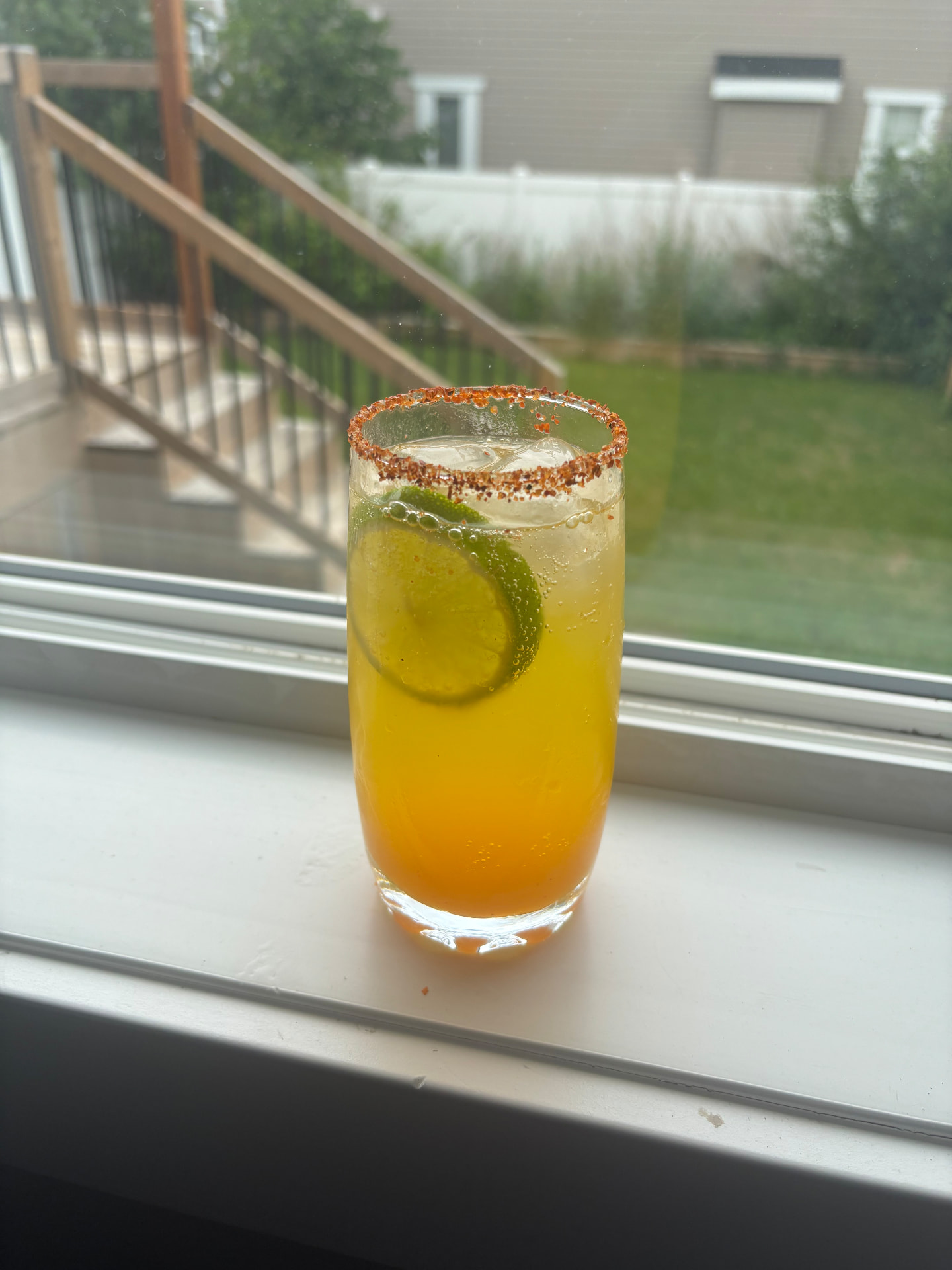 Tajin-rimmed citrus mocktail with lime wheels by a sunlit window